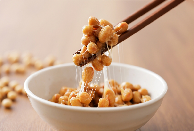 Natto, a natural fermented source of vitamin K2, lifted with chopsticks